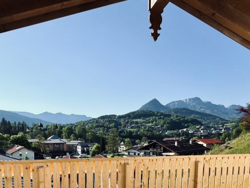 Der Panoramablick reicht bis tief in die Berchtesgadener Alpen Blick auf eine Berglandschaft mit Häusern und blauem Himmel.