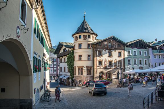 Marktplatz Berchtesgaden Stadtplatz mit historischem Gebäude und Außenterrassen unter klarem Himmel.