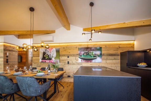 Der freistehende Küchenblock integriert sich nahtlos in den Essbereich Moderne Küche mit Holzelementen, Esstisch und stilvollen Lampen.