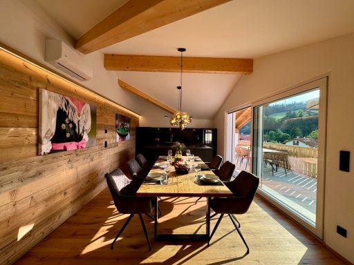 Der großzügige Essbereich bietet ausreichend Platz für bis zu sieben Personen Moderne Esszimmer mit Holzdecke, großer Tisch und Blick auf die Landschaft.