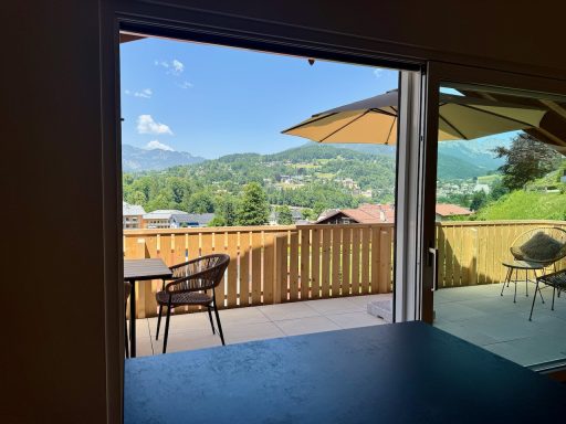 Kochen mit Panoramablick auf die Berchtesgadener Alpen Blick auf einen Balkon mit Stühlen, Tischen und bergiger Landschaft im Hintergrund.